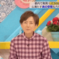 a woman wearing a purple plaid shirt is sitting in front of a sign that says ' tokyo ' on it