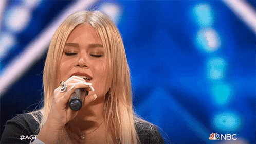a woman is singing into a microphone on nbc 's america 's got talent