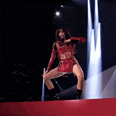 a woman in a red crop top and skirt is dancing on a stage
