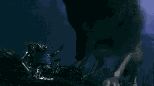 a person is reaching out towards a monster in the dark with a full moon in the background .