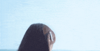 a close up of a woman 's head with a hair clip in her hair looking at the ocean .