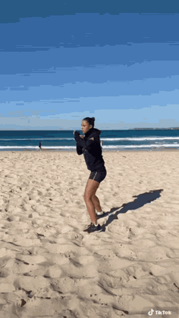 a woman is doing squats on the beach with a tiktok watermark on the bottom