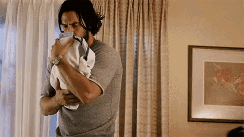 a man is holding a newborn baby in his arms in a room .