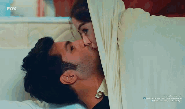a man and a woman are kissing under a blanket with the fox logo in the corner