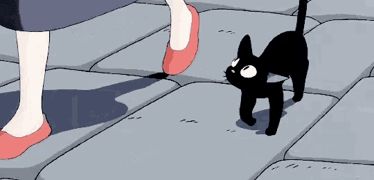 a black cat is walking next to a woman 's feet on a sidewalk .