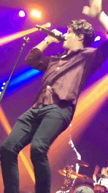 a man singing into a microphone with his arms outstretched