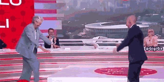 a man in a suit is dancing with a woman in a blue suit on a stage