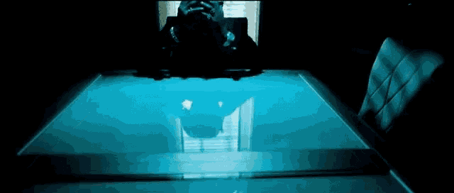a person is sitting at a table with a blue light shining on it