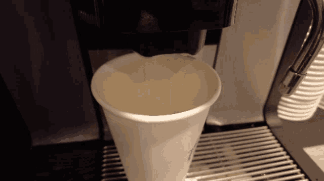 a paper cup is being poured into a coffee maker