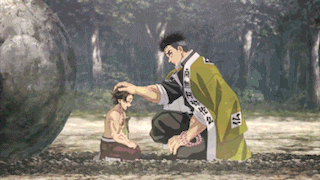 a man in a green robe is petting a child 's head while kneeling down in the dirt .