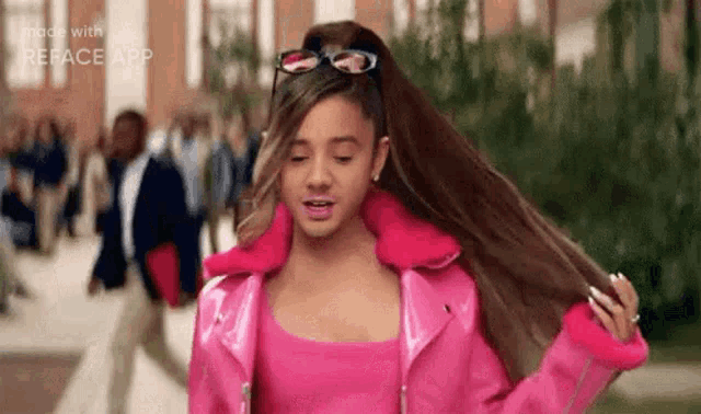 ariana grande is wearing a pink jacket and sunglasses and holding her hair in a ponytail .
