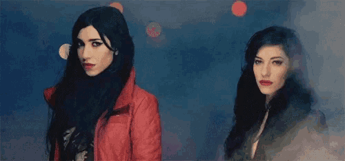a woman in a red jacket stands next to another woman with dark hair