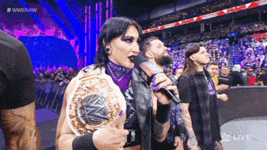 a woman is holding a wrestling championship while speaking into a microphone ..