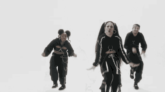 a group of people in black clothes are dancing together on a white background
