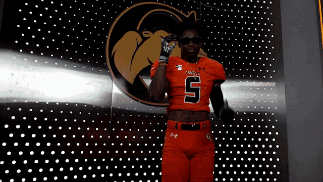 a football player wearing an orange jersey with the number 5 on it