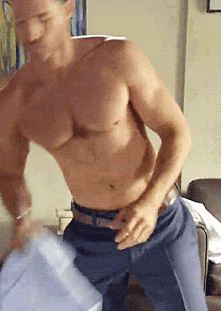 a shirtless man in blue pants is standing in a room