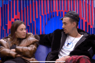 a man and a woman are sitting next to each other on a couch and talking .