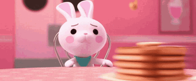 a stuffed bunny is sitting at a table with a stack of pancakes