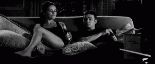 a man and a woman are sitting on a couch watching a movie .
