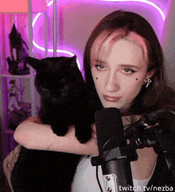 a woman holding a black cat in front of a microphone with twitch.tv/nezba on the bottom right