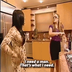 two women standing in a kitchen with one saying " i need a man "