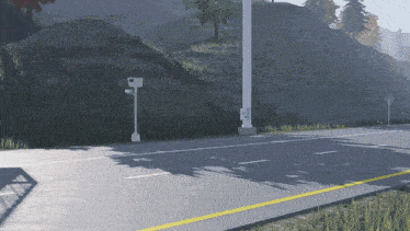 a camera on a pole on the side of a road next to a grassy hill