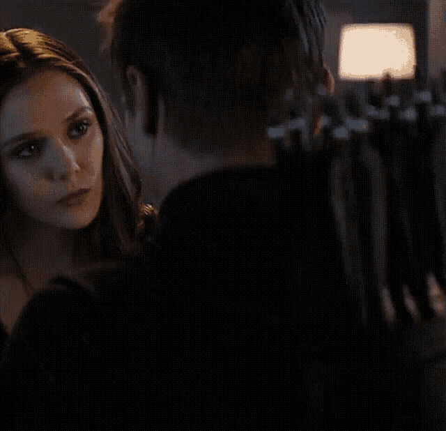 a man and a woman are looking at each other in the dark