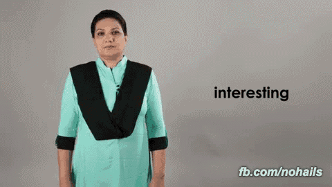 a woman in a blue shirt is making a sign that says interesting .