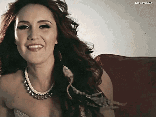 a woman with red hair is smiling and wearing a necklace with gifsavnon written on the bottom