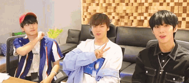 three young men are sitting at a table and one of them is wearing a shirt that says ' forever ' on it