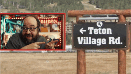 a man points to a sign that says teton village road