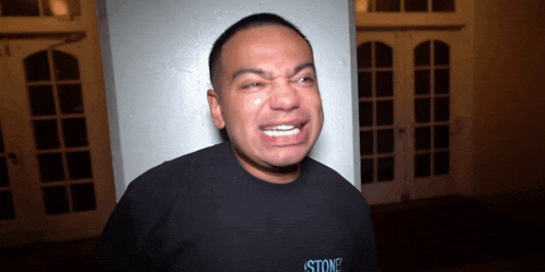 a man wearing a black shirt that says stone on it is crying