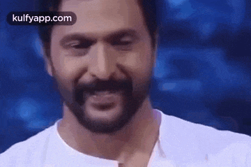 a man with a beard and mustache is smiling and looking at the camera .