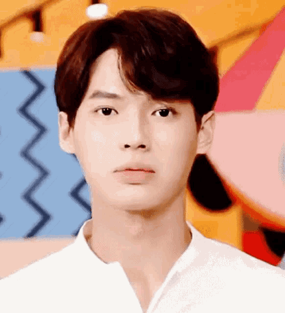 a close up of a young man 's face in front of a colorful wall .