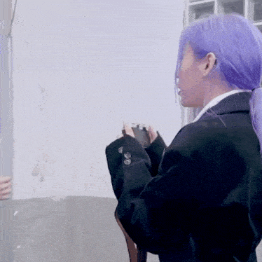 a woman with purple hair is taking a picture with a camera