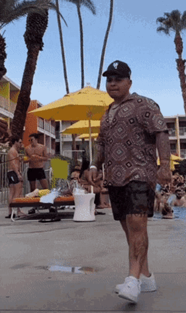 a man wearing a ny hat is walking across a pool