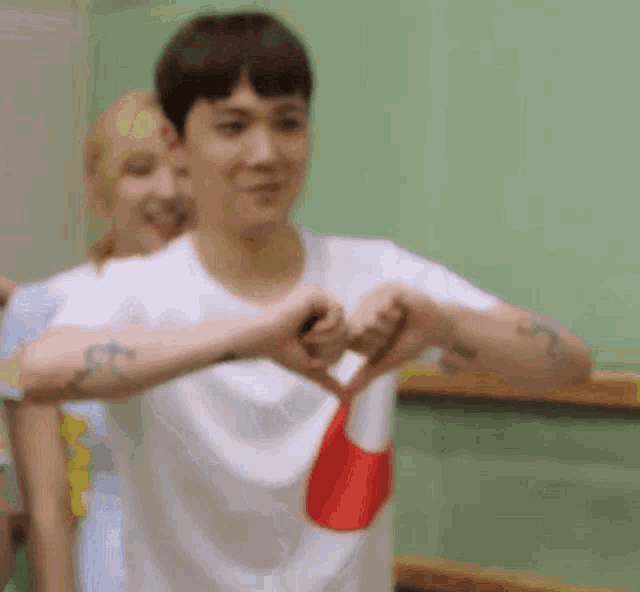 a young man is making a heart shape with his hands .