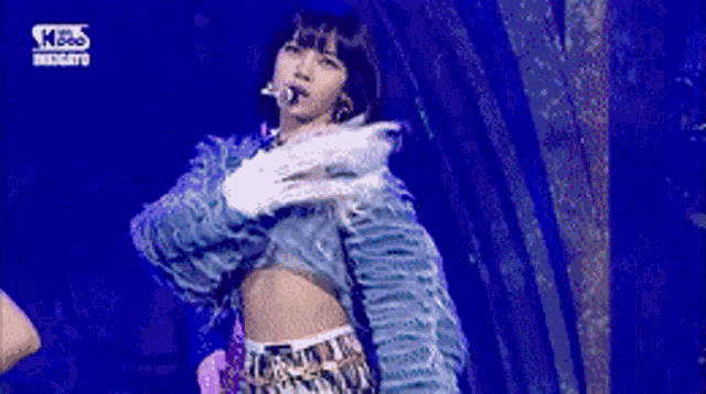 a woman is dancing on a stage with a blue background .