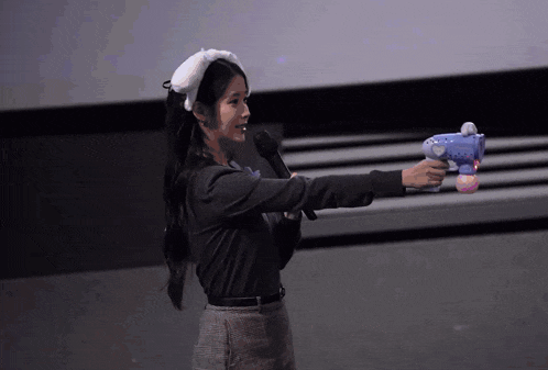 a woman holding a microphone and a blue toy gun