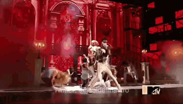 a group of people are dancing on a stage with a twitter logo in the corner