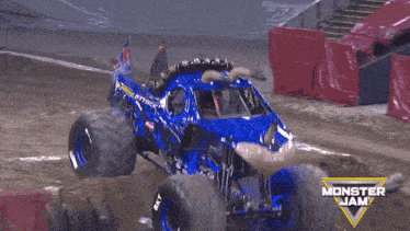 a blue monster jam truck is driving down a dirt road