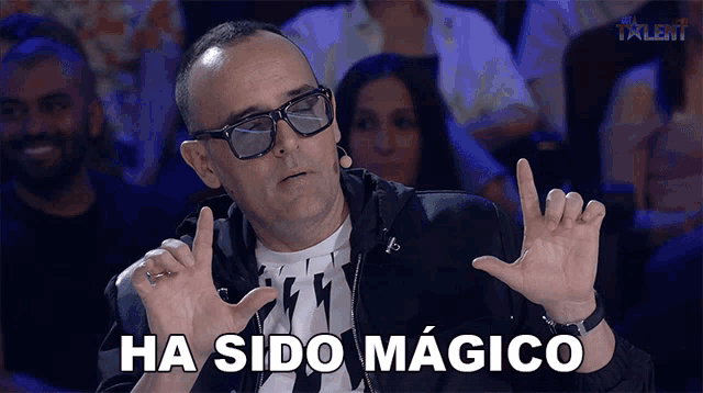 a man wearing glasses says ha sido magico in front of a crowd of people