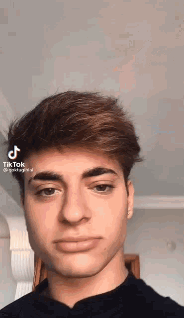 a young man is making a funny face with a tik tok app on his phone