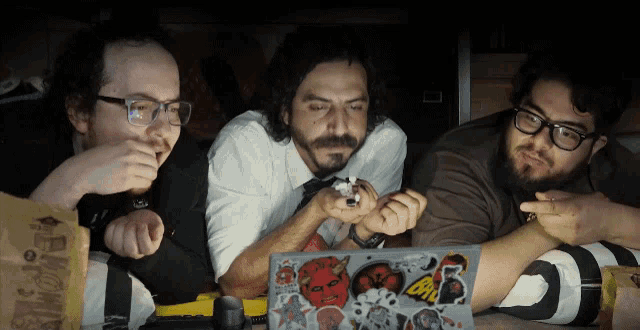 a group of men are looking at a laptop with stickers on it including one that says oni