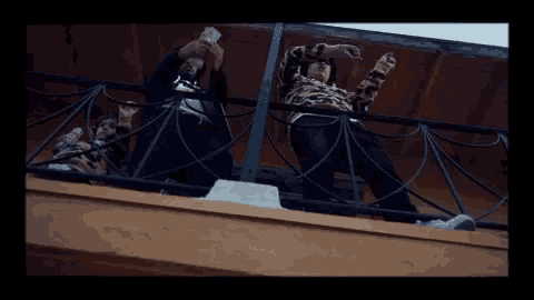 a group of people standing on a balcony with their hands in the air