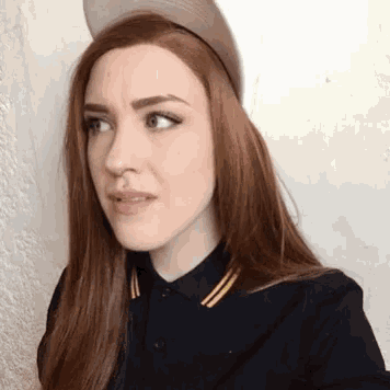 a woman wearing a hat and a black shirt is making a face