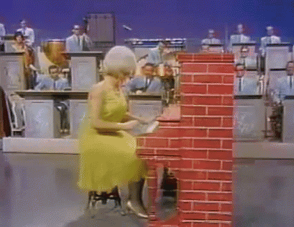 a woman in a yellow dress is playing a piano in front of an orchestra ..