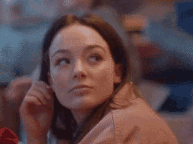 a woman is sitting at a table with her hand on her chin and looking to the side .
