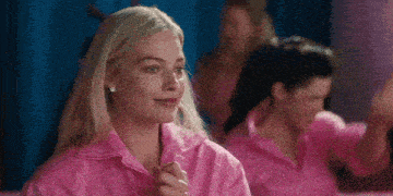 a woman in a pink shirt is sitting in front of a group of women .