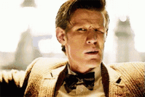 a man in a suit and bow tie is sitting on a couch making a funny face .